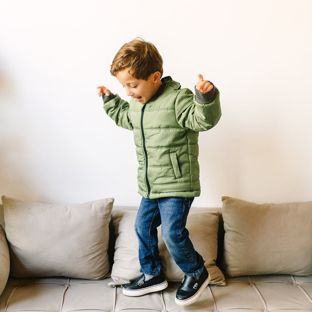 Puff/Green 
Little boy with brown hair is wearing a green car seat coat.  The coat is zipped and the boy is jumping on a beige couch.